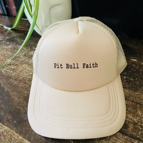 Cream/white trucker hat with bold “Pit Bull Faith” text, breathable mesh back, adjustable strap.